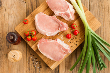 Свежие стейки из отборного мяса на деревянной доске с овощами и специями. вид сверху - MarinaMos