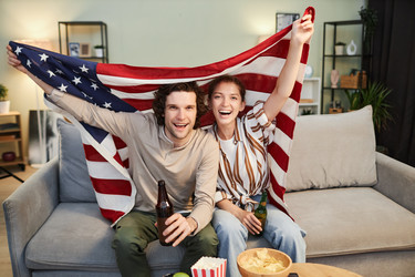Пара, размахивающая флагом США и болеющая за спортивный матч дома - SeventyFour