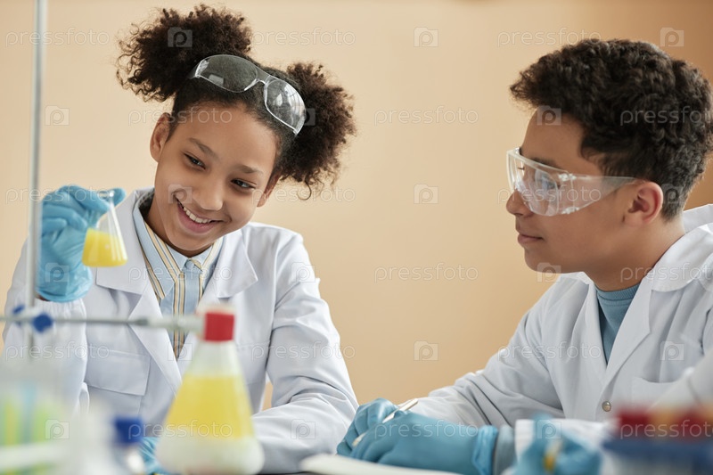 Smiling black girl in school watching chemical reaction