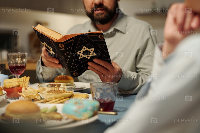 Cropped shot of bearded man with open Torah reading Psalms or other text