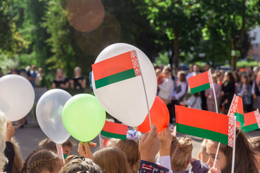 Торжественный митинг возле школы, посвященный Дню знаний в Республике Беларусь. Дети держат в руках национальную символику, флаги и мячи красного и зеленого цветов - AliakseiSmalenski