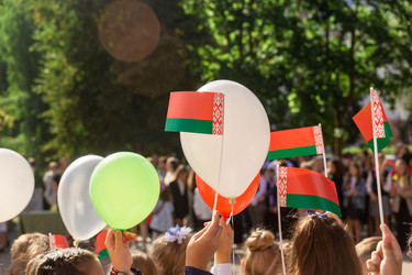 Торжественный митинг возле школы, посвященный Дню знаний в Республике Беларусь. Дети держат в руках национальную символику, флаги и мячи красного и зеленого цветов - AliakseiSmalenski