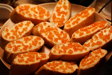 Традиционные праздничные бутерброды с красной икрой и маслом на тарелке - SABINAPHOTO