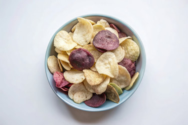 Яркое сочетание вкуснейших домашних картофельных чипсов в миске на чистой поверхности. Генеративный ИИ - RomanZ