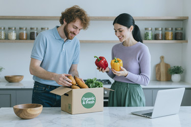 Взрослая пара распаковывает доставленные органические продукты на кухне. - AnnaStills