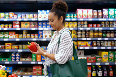 Темнокожая женщина сравнивает свежие продукты во время похода в продуктовый магазин. - SeventyFour