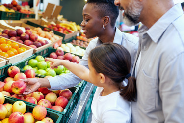 Семья блэк выбирает свежие яблоки во время совместного похода в продуктовый магазин. - SeventyFour