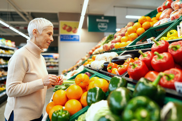 Пожилая женщина выбирает свежие продукты для здоровых покупок в продуктовом магазине. - SeventyFour