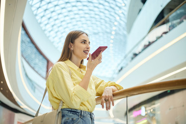 Взрослая женщина использует голосовое сообщение на смартфоне для совершения покупок через мобильное приложение. - SeventyFour