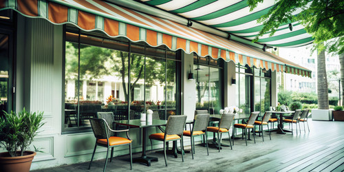 A vibrant café terrace with an orange awning welcomes guests for relaxing moments in a charming urban setting during daylight hours. Generative AI - RomanZ