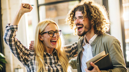 Two friends celebrate a success indoors, smiling with enthusiasm at a modern café. Generative AI - RomanZ