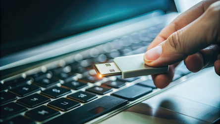 Человек вставляет USB-флешку в ноутбук на рабочем месте. Генеративный ИИ - RomanZ