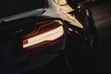 Задние фонари спортивного автомобиля BMW M2 светятся в темное вечернее время - Pippocarlot