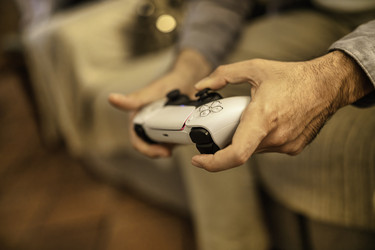 Мужчина играет в видеоигру с помощью контроллера PlayStation 5 - Pippocarlot