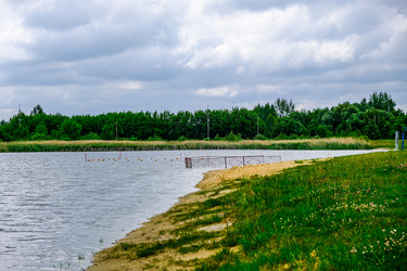 Берег озера с песчаным пляжем и металлической оградой в воде - Derbis