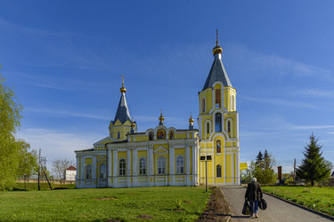 Желтый православный храм Успения Пресвятой Богородицы (Успенская церковь) с двумя колокольнями и куполами в сельском пейзаже. Лихославль, Тверская область - Sadoff