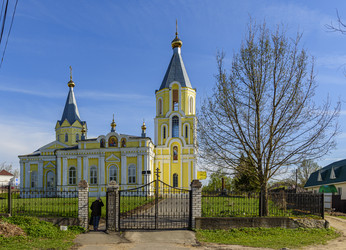 Желтый православный храм Успения Пресвятой Богородицы (Успенская церковь) с двумя колокольнями и куполами в сельском пейзаже. Лихославль, Тверская область - Sadoff