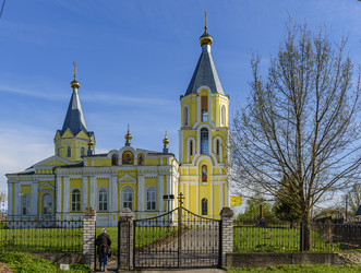 Желтый православный храм Успения Пресвятой Богородицы (Успенская церковь) с двумя колокольнями и куполами в сельском пейзаже. Лихославль, Тверская область - Sadoff