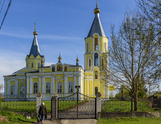 Желтый православный храм Успения Пресвятой Богородицы (Успенская церковь) с двумя колокольнями и куполами в сельском пейзаже. Лихославль, Тверская область - Sadoff