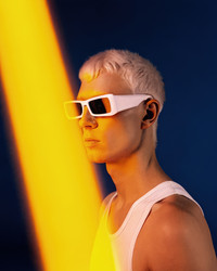 Молодой человек с короткими седыми волосами и в солнцезащитных очках позирует на ярком фоне. Генеративный искусственный интеллект - RomanZ