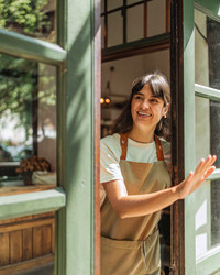 A Young Baker Welcoming Customers at Her Bustling Bakery and Café. Generative AI - RomanZ