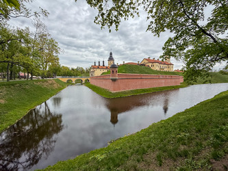 Несвиж, Беларусь - 28 апреля 2025 года: Несвижский замок. Замок с кирпичными стенами, арочным мостом и башней под пасмурным небом. Средневековый замок в Беларуси. Крепость с кирпичными стенами, арочным мостом и башней под пасмурным небом - steveee