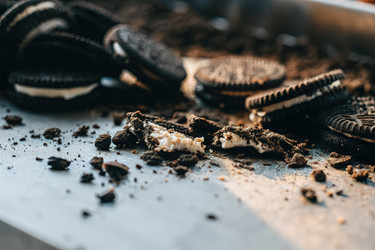 Измельченные кусочки печенья Oreo, разбросанные по серебристой поверхности, рядом лежат целые печенья. Генеративный ИИ - RomanZ