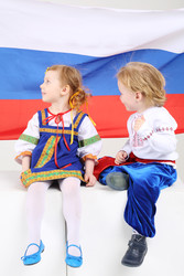 Мальчик и девочка в народных костюмах сидят и смотрят на русский флаг - paha_l