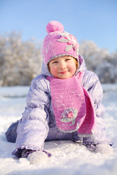 Маленькая счастливая девочка в розовом шарфе и шапочке лежит на снегу и смотрит на - paha_l