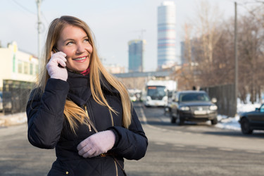 Девушка в теплой одежде разговаривает по телефону на улице на фоне небоскребов - paha_l