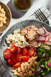 Полезный салат из тунца с белой фасолью, сыром фета, помидорами, редисом и зеленью на мраморном столе - Irrin0215
