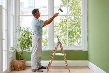 Мужчина искусно красит стену в ярко-зеленый цвет в светлой комнате, демонстрируя новаторские идеи по благоустройству дома - Neirfy