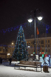 Заснеженная городская площадь с новогодней елкой и праздничной иллюминацией ночью - SanPhoto