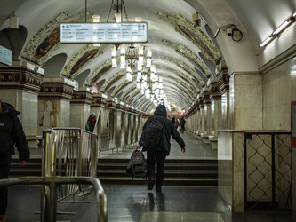 Пассажир с рюкзаком идет по богато украшенному залу московского метро - SanPhoto