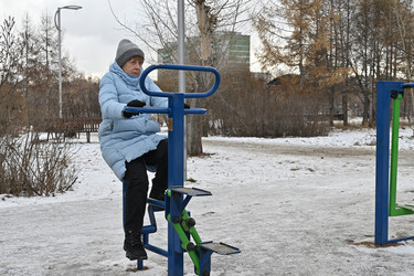 Женщина занимается спортом в заснеженном парке возле зданий зимой в городе - VetalanaS