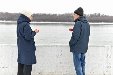 Двое человек идут по заснеженной тропинке возле реки в пасмурный зимний день - VetalanaS