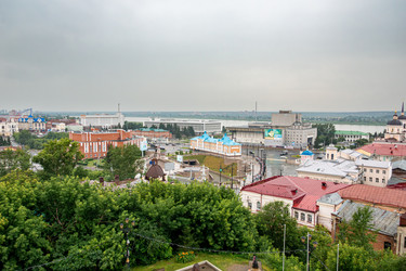 Томск, Россия - 6 июля 2025 года. В центре города стоит коммерческое здание начала XX века. Каменный мост через реку Ушайка соединяет городские районы под пасмурным небом. Выборочная фокусировка - dkorostilev78