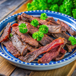 Вкусная вяленая говядина, приготовленная в аэрогриле, подается на блюде со свежей зеленью. Генеративный искусственный интеллект - RomanZ