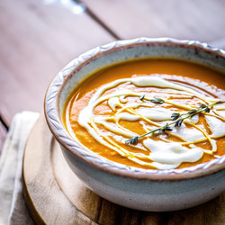 Сливочный суп из тыквы сорта «баттернат» с апельсиновым вкусом, подается в деревенской миске на деревянном столе. Генеративный искусственный интеллект - RomanZ