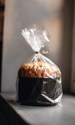 Вкусный панеттоне, завернутый в целлофановый пакет, на деревянном столе. Генеративный искусственный интеллект - RomanZ