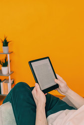 Человек читает электронную книгу, удобно расположившись в уютном кресле в помещении. Генеративный искусственный интеллект - RomanZ