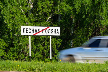 Дорожный знак, конец города Лесная Поляна, или Лесная Поляна, город-спутник Кемерово, зеленый лес, трава и серый автомобиль, размытый из-за движения транспорта - dkorostilev78