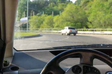 Руль и лобовое стекло с пятнами от дворников, автомобиль движется по кругу в сельской местности, следуя за старым автомобилем, выборочная фокусировка - dkorostilev78