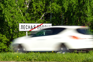 Дорожный знак, конец города Лесная Поляна, или Лесная Поляна, город-спутник Кемерово, зеленый лес, трава и белый автомобиль, испачканный в грязи из-за пробки - dkorostilev78