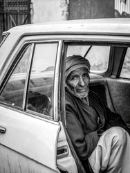Пожилой иранец сидит в машине Peykan на городской улице. Генеративный искусственный интеллект - RomanZ
