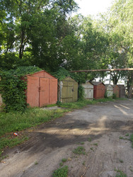 Гаражный кооператив металлический гараж в городе окрашенный краской в зарослях кустарника заброшенный участок - qwulity