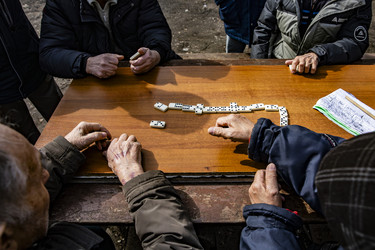 Пожилые люди играют в домино за деревянным столом на улице - Xandery
