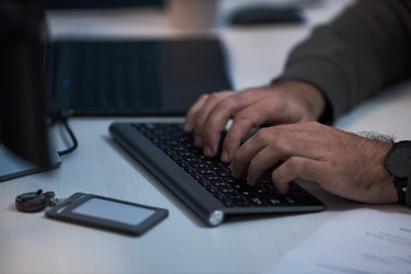 Взрослый мужчина печатает на клавиатуре, выполняя офисную работу по вводу данных. - DragonImagesAsia