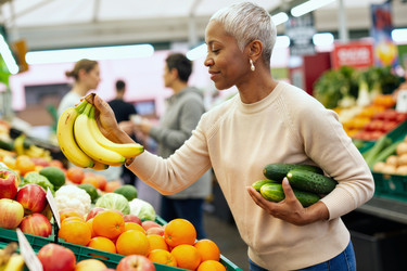 Темнокожая женщина выбирает свежие продукты для здоровых покупок в продуктовом магазине. - SeventyFour