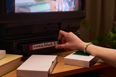 Подросток вставляет vhs-кассету в видеомагнитофон для домашнего просмотра. - Pressmaster